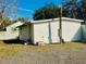 Rear view of outbuilding featuring white vinyl siding, a functional door and windows, and a neutral-toned gravel yard at 18633 14Th Ave, Orlando, FL 32833