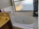 A soaking tub is next to the vanity with a frosted window above it in the bathroom at 250 Sir Phillips Dr, Davenport, FL 33837