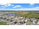 An aerial view shows homes with solar panels situated near a serene lake and expansive green fields at 293 Pineywoods St, St Cloud, FL 34772