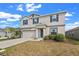 Two-story home featuring neutral colors, dark shutters, attached garage, and green landscaping under a blue, partly cloudy sky at 293 Pineywoods St, St Cloud, FL 34772