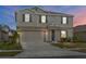 Exterior of a two-story home showcasing neutral colors, dark shutters, an attached garage and well-manicured landscaping at 293 Pineywoods St, St Cloud, FL 34772