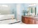 Bright bathroom with granite countertop, dark wood vanity, and large tub with tiled accents at 3100 Stonewyck St, Orlando, FL 32824