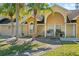 Inviting townhome exterior with lush landscaping, palm trees, and a cozy front porch sitting area at 3112 Enclave Ct, Kissimmee, FL 34746