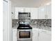 Modern kitchen features stainless steel appliances, white cabinets, and stylish backsplash at 410 Lark Ct, Kissimmee, FL 34759