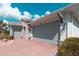 Garage featuring three doors, a brick driveway, and manicured landscaping at 461 Treviso Dr, Poinciana, FL 34759