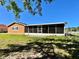View of screened-in patio area and grassy backyard under a bright blue sky at 602 N Delmonte Ct, Kissimmee, FL 34758