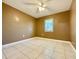 Neutral bedroom with a ceiling fan, tile flooring, and a window with blinds for natural light at 602 N Delmonte Ct, Kissimmee, FL 34758