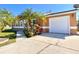 A well-maintained home featuring a garage with white door and palm tree in the front yard at 602 N Delmonte Ct, Kissimmee, FL 34758