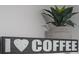 Close-up of I <3 Coffee sign with potted plant on a shelf at 6165 Carrier Dr # 2108, Orlando, FL 32819