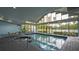 Indoor pool with hot tub surrounded by floor-to-ceiling windows and table with chairs at 6165 Carrier Dr # 2108, Orlando, FL 32819