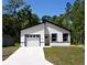 Modern, newly constructed single-story home with a bright white exterior, dark trim and an attached garage at 6862 Se 23Rd Ave, Ocala, FL 34480