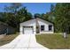 Modern, newly constructed single-story home with a bright white exterior, dark trim and an attached garage at 6862 Se 23Rd Ave, Ocala, FL 34480