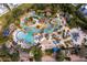 Aerial view of a community pool featuring lazy river, water slides, lounge chairs, and lush tropical landscaping at 7848 Somersworth Dr, Kissimmee, FL 34747