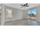 Bright bedroom with light grey wood floors, ceiling fan and sliding glass doors to a balcony at 7921 Jacks Club Dr, Kissimmee, FL 34747