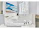 A close up on a corner tub with tile surround, ocean artwork and gray vanity countertop at 8462 Secret Key Cv, Kissimmee, FL 34747