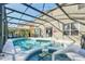 Screened-in pool with spa, sun loungers, and outdoor dining area at 8462 Secret Key Cv, Kissimmee, FL 34747