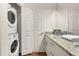 Convenient laundry area featuring a stacked washer and dryer, alongside a stylish bathroom sink and counter setup at 8982 Shine Drive, Kissimmee, FL 34747