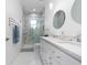 Bright bathroom features double vanity, walk-in shower with marble style tile, and modern fixtures at 13049 Sunshine Cir, Clermont, FL 34711