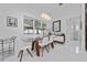 Bright dining room features glass table, modern chandelier, large window, and sleek white furnishings at 13049 Sunshine Cir, Clermont, FL 34711