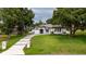 Beautiful single-story home with a well-manicured lawn and a long, grand driveway lined with trees at 13049 Sunshine Cir, Clermont, FL 34711
