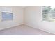 Cozy bedroom boasts neutral walls, carpet, and two sunny windows at 1418 Delaware Ave, St Cloud, FL 34769