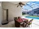 Outdoor dining area with a ceiling fan overlooking a screened-in pool and spa at 151 Saragossa Ave, Davenport, FL 33897