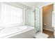 Modern bathroom showcasing a tiled tub with window and separate glass shower, and wood-look tile flooring at 153 Laurel Ridge Pass, Davenport, FL 33897