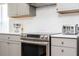 Close-up of a modern range with stainless steel appliances, white backsplash, and light gray cabinets at 153 Laurel Ridge Pass, Davenport, FL 33897