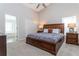 Well-lit main bedroom featuring a wooden bed frame and carpet, with an ensuite bath visible through an open door at 153 Laurel Ridge Pass, Davenport, FL 33897