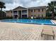 Community pool with crisp blue water next to a condo with a fenced perimeter and a chair nearby at 175N Pearl Lake Cswy # 114, Altamonte Springs, FL 32714