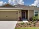 Tan single-story home with a two car garage and a well manicured front yard at 1919 Escambia Ln, Kissimmee, FL 34759