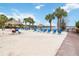 Sandy beach with blue lounge chairs, tiki umbrellas, and a peaceful lake view at 313 Lucaya Loop # 313, Davenport, FL 33897