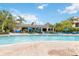 Resort style pool with bright blue sun loungers, umbrellas, and palm trees under a sunny sky at 313 Lucaya Loop # 313, Davenport, FL 33897