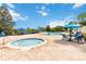 Community pool and spa with blue lounge chairs, umbrellas, and a view of the sunny neighborhood at 313 Lucaya Loop # 313, Davenport, FL 33897