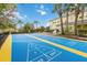 Community shuffleboard court with yellow trim surrounding a yellow resort building with palm trees at 313 Lucaya Loop # 313, Davenport, FL 33897