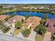 Aerial view of homes with well-manicured lawns, brick driveways, and a serene lake in a desirable neighborhood at 3390 Fallbrook Dr, Kissimmee, FL 34759