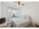 Bright bedroom featuring floral bedding, a ceiling fan, and a large window at 3390 Fallbrook Dr, Kissimmee, FL 34759