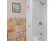 Bathroom features a white tub with shower, tiled walls, and a decorative wall art at 401 Woodlawn Ter, Kissimmee, FL 34744