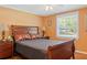 The bedroom features a wood bed frame, orange colored walls, and a window at 401 Woodlawn Ter, Kissimmee, FL 34744
