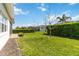 Well-maintained backyard featuring lush green grass, privacy hedges, and a brick pathway leading to the side of the home at 4918 Drawdy Ct, St Cloud, FL 34772