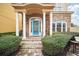 Inviting front porch with stone pillars, blue front door, and manicured shrubs at 7623 Excitement Dr, Reunion, FL 34747