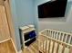 Baby room featuring a crib, wall-mounted TV, and a shelving unit with neatly folded towels at 7660 Otterspool St, Kissimmee, FL 34747