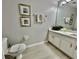 Bright bathroom with a toilet, vanity with white cabinets, framed artwork, and a large mirror at 7660 Otterspool St, Kissimmee, FL 34747