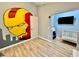 Bedroom with hardwood floors, an Iron Personal wall mural and an opening leading to the baby's crib at 7660 Otterspool St, Kissimmee, FL 34747