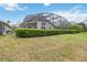 Green backyard featuring a large screened-in patio, manicured hedges, and clear blue skies at 8122 Yellow Crane Dr, Kissimmee, FL 34747