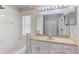 Bright bathroom features a tub with shower, neutral tile floor, and a vanity with a large mirror and cabinets at 8122 Yellow Crane Dr, Kissimmee, FL 34747