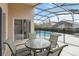 The screened patio features a dining set and a view of the pool and the surrounding fenced yard at 8122 Yellow Crane Dr, Kissimmee, FL 34747