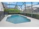 Aerial view of an inviting in-ground pool surrounded by a screen enclosure and manicured hedges at 8122 Yellow Crane Dr, Kissimmee, FL 34747