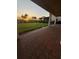 Covered patio with brick pavers leads to a lush backyard with mature palms at sunset at 8289 Topsail Pl, Winter Garden, FL 34787