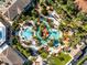 An aerial view of a pool and waterpark featuring lush landscaping, winding pools, lounge areas, and vibrant umbrellas at 841 Retreat Blvd # 101, Davenport, FL 33897